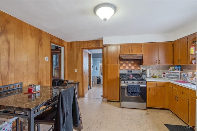 kitchen with stainless steel range with gas cooktop, wooden walls, and decorative backsplash