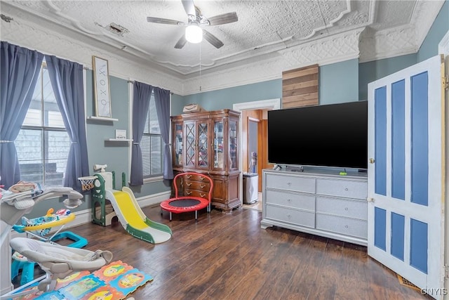 playroom featuring dark hardwood / wood-style flooring, crown molding, a textured ceiling, and ceiling fan