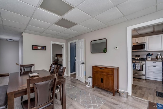 dining room with a paneled ceiling and light wood-type flooring