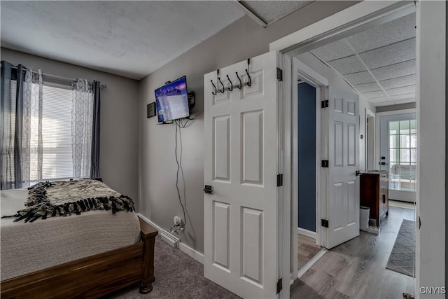 bedroom with a paneled ceiling and light wood-type flooring