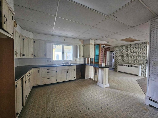 kitchen with a paneled ceiling, sink, radiator heating unit, and kitchen peninsula