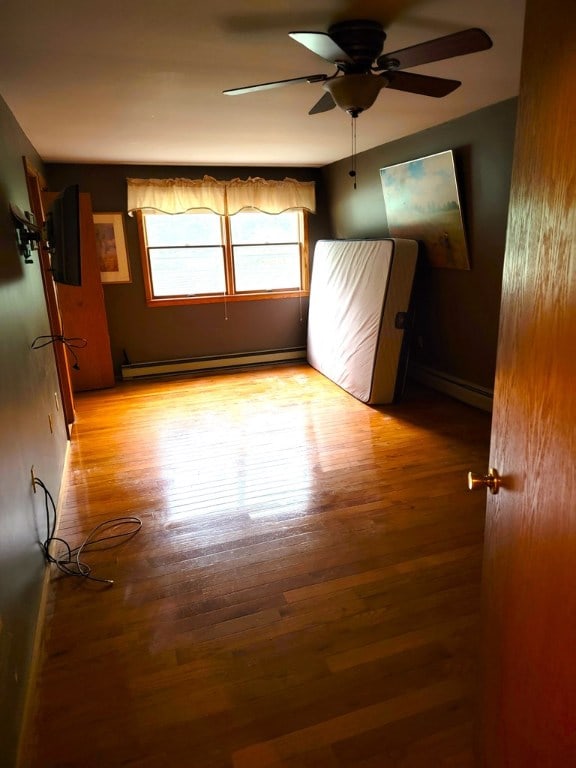 interior space featuring ceiling fan, light hardwood / wood-style flooring, and a baseboard heating unit