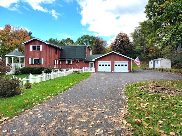 view of front of home with a shed, a garage, and a front yard