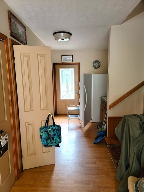 corridor with light hardwood / wood-style flooring and a textured ceiling