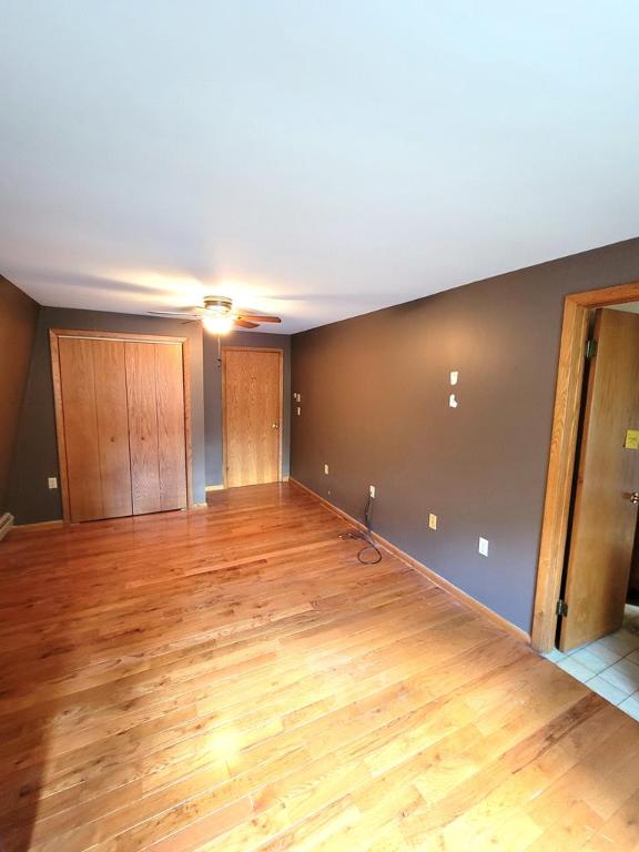 interior space featuring multiple closets, light hardwood / wood-style flooring, and ceiling fan