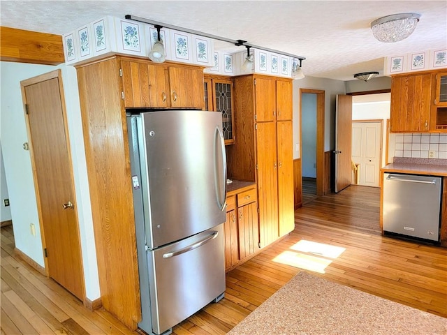 3530 Coats Rd, Hector, NY 14818 - kitchen with appliances with stainless steel finishes, light wood finished floors, brown cabinets, a textured ceiling, and glass insert cabinets