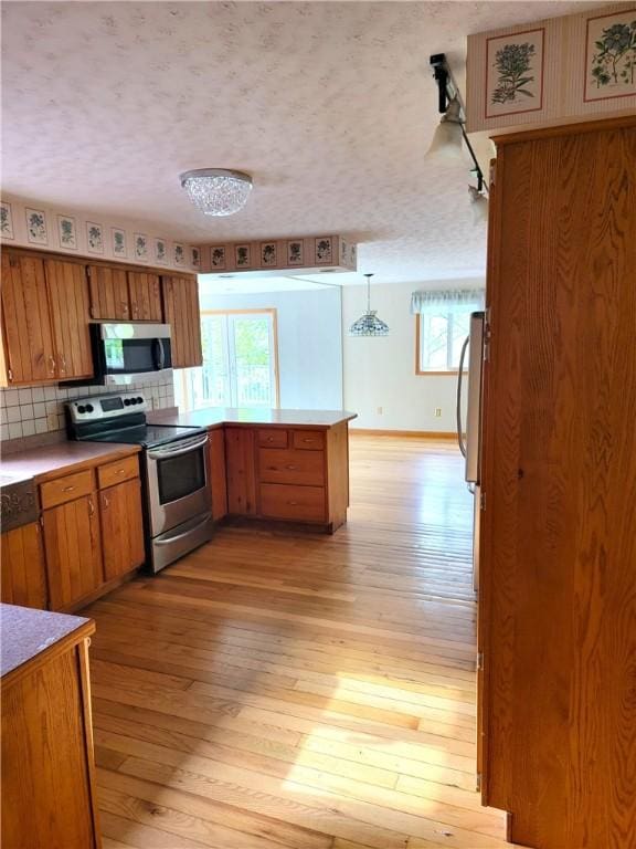 3530 Coats Rd, Hector, NY 14818 - kitchen featuring appliances with stainless steel finishes, brown cabinets, a peninsula, and light wood finished floors