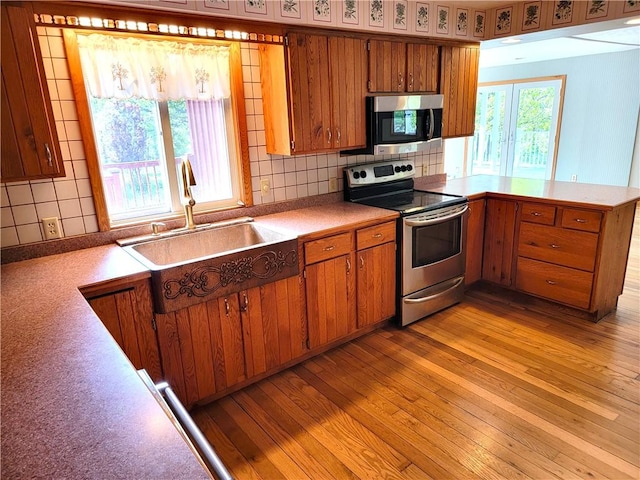 3530 Coats Rd, Hector, NY 14818 - kitchen with stainless steel appliances, brown cabinetry, a sink, light wood-style flooring, and a peninsula