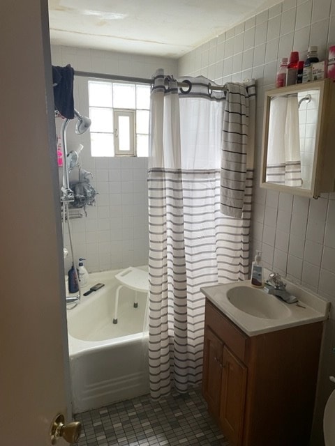 bathroom with shower / bath combo with shower curtain, vanity, tile patterned flooring, and tile walls