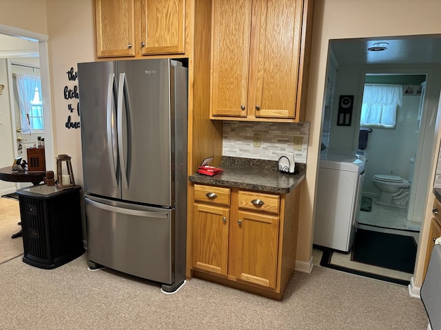 kitchen with tasteful backsplash, washer / clothes dryer, and stainless steel refrigerator