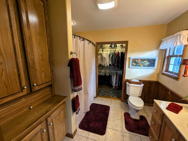 bathroom with vanity, tile patterned flooring, wooden walls, and toilet