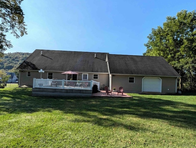 back of property featuring a garage, a deck, and a lawn