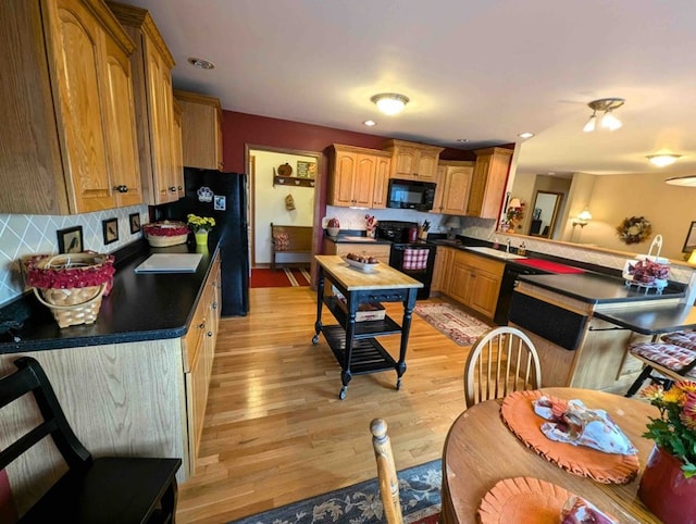 kitchen featuring sink, decorative backsplash, light hardwood / wood-style flooring, and black appliances