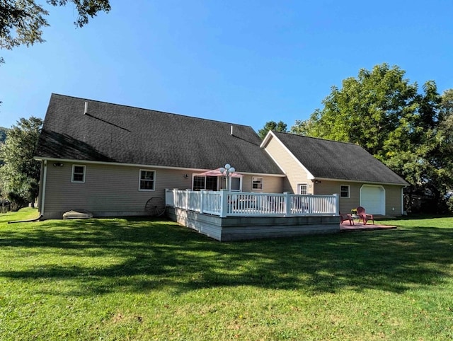 back of property with a garage, a yard, and a deck