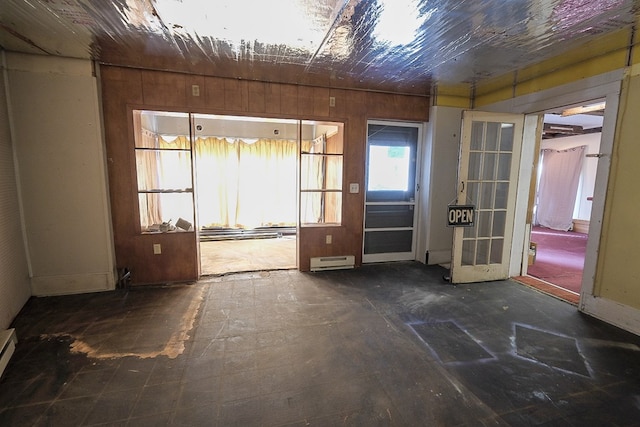 interior space with a baseboard radiator and wood walls