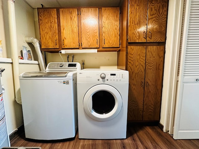 laundry area featuring dark wood-type flooring, cabinets, and washing machine and dryer