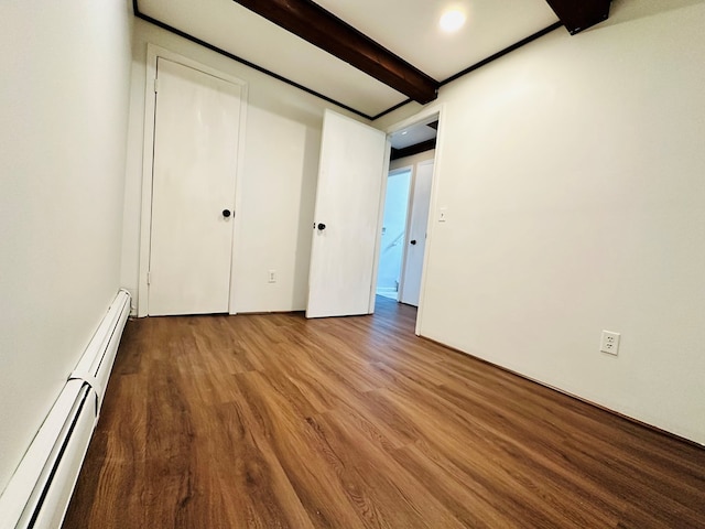 unfurnished bedroom with hardwood / wood-style flooring, beam ceiling, and a baseboard heating unit