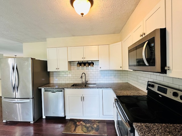 kitchen with white cabinetry, sink, stainless steel appliances, and dark stone countertops