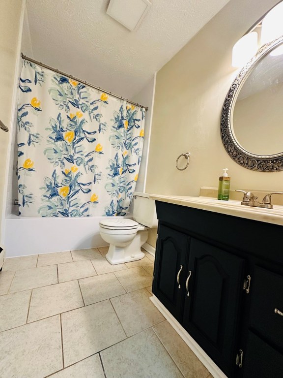 full bathroom with shower / tub combo with curtain, tile patterned floors, toilet, a textured ceiling, and vanity