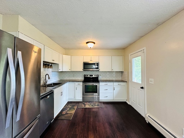 kitchen featuring appliances with stainless steel finishes, white cabinetry, sink, dark hardwood / wood-style flooring, and a baseboard heating unit