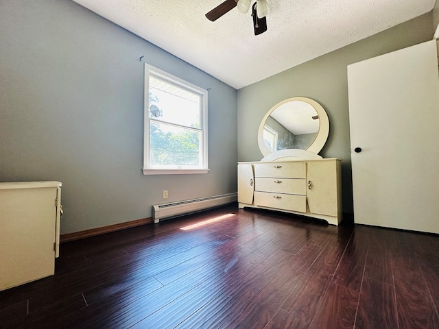 unfurnished bedroom with ceiling fan, a baseboard heating unit, dark wood-type flooring, and a textured ceiling