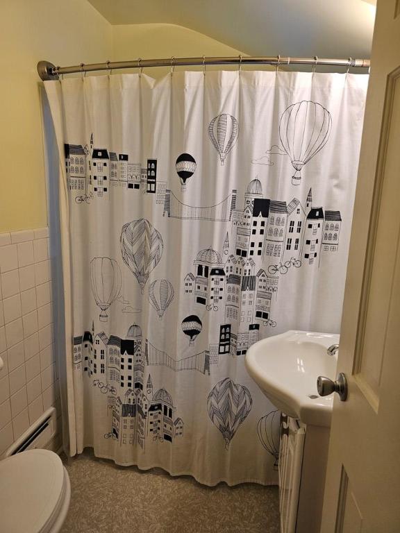 bathroom with baseboard heating, toilet, curtained shower, and tile walls