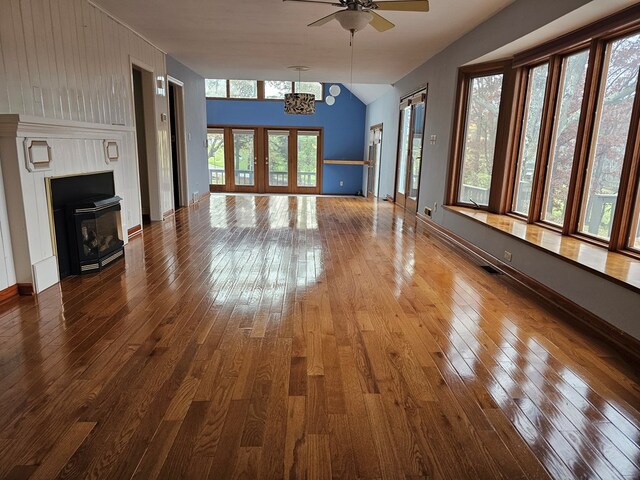 unfurnished living room with hardwood / wood-style flooring, lofted ceiling, and ceiling fan with notable chandelier