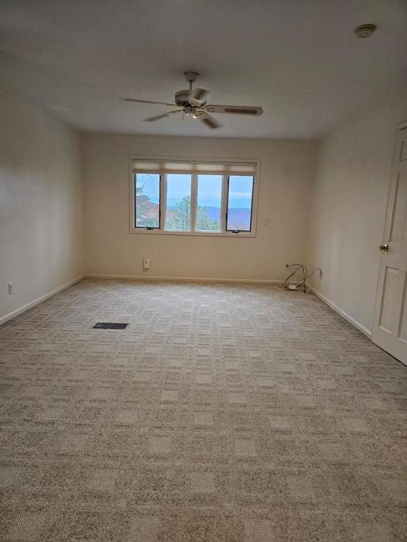 spare room with ceiling fan and light carpet