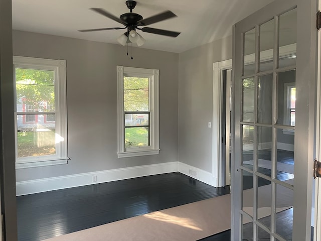 empty room with a healthy amount of sunlight, hardwood / wood-style floors, and ceiling fan