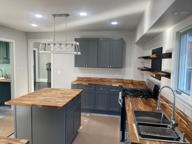 kitchen featuring pendant lighting, sink, stainless steel range with gas stovetop, and wood counters