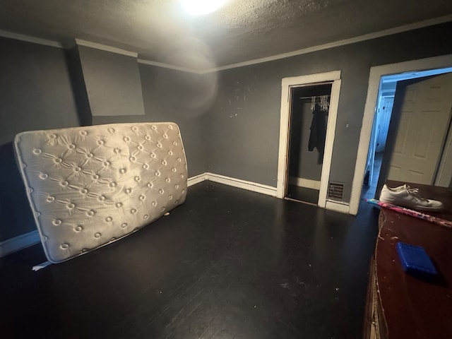 bedroom with hardwood / wood-style flooring, ornamental molding, a closet, and a textured ceiling