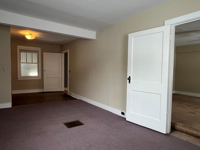 carpeted empty room featuring beam ceiling