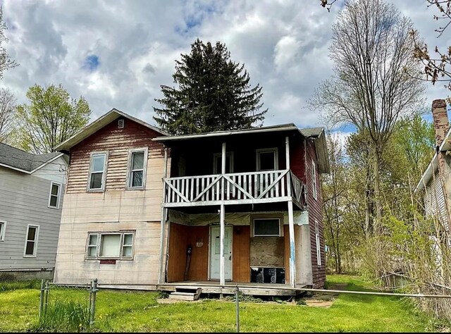 back of house featuring a balcony and a yard