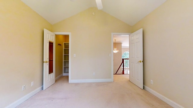 unfurnished bedroom with light carpet, a walk in closet, and vaulted ceiling