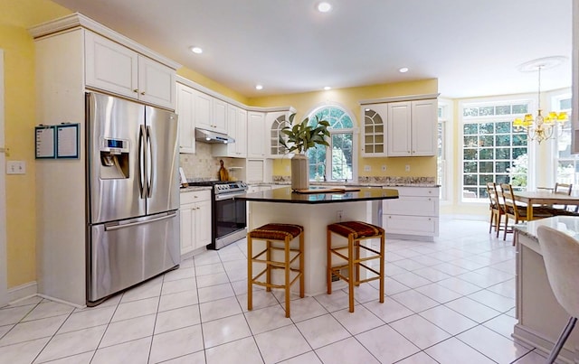 kitchen featuring white cabinets, a kitchen breakfast bar, light tile patterned floors, stainless steel appliances, and plenty of natural light