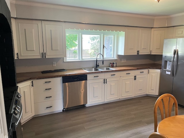 kitchen featuring sink, white cabinetry, stainless steel appliances, dark hardwood / wood-style floors, and ornamental molding