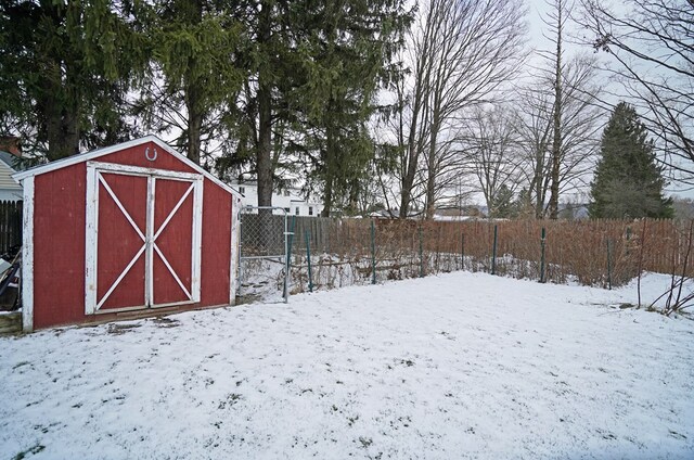 yard covered in snow featuring a storage shed