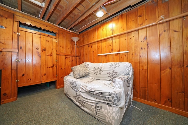 living area with dark colored carpet and wood walls