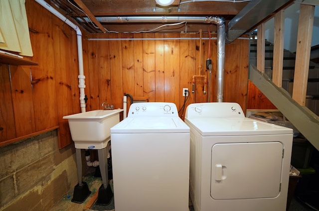 laundry area with washer and dryer, sink, and wood walls