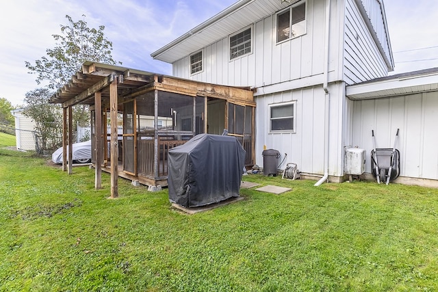 rear view of house with a lawn and a sunroom