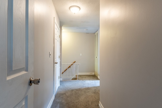 hallway with light carpet and a textured ceiling