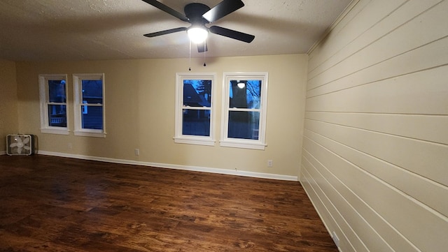 empty room featuring ceiling fan, dark wood-type flooring, and a textured ceiling