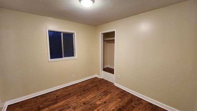 unfurnished bedroom featuring a closet, dark hardwood / wood-style floors, and a textured ceiling