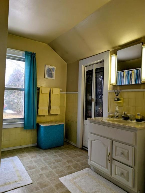 interior space with vanity, vaulted ceiling, and tile walls