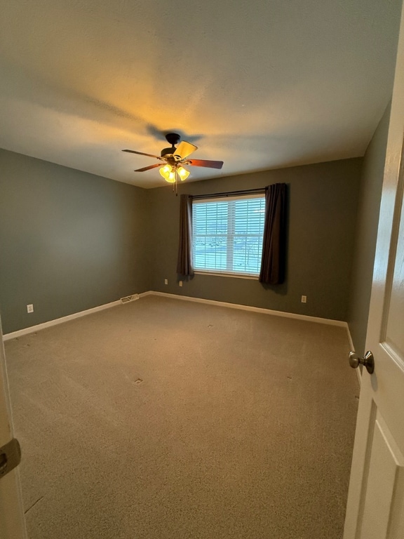 carpeted spare room with ceiling fan