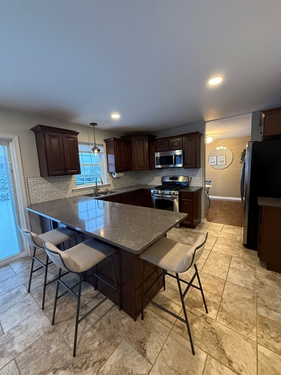 kitchen featuring pendant lighting, sink, a breakfast bar, stainless steel appliances, and kitchen peninsula