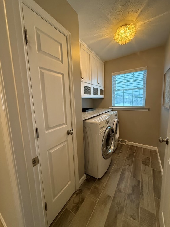 washroom with cabinets, a textured ceiling, and washer and clothes dryer