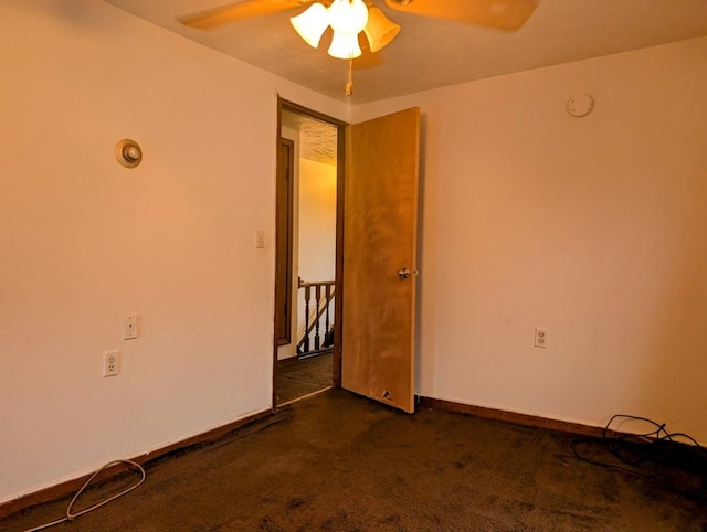 unfurnished room featuring ceiling fan and dark colored carpet