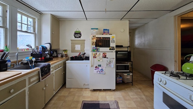 kitchen featuring washer / clothes dryer, white appliances, a paneled ceiling, and sink