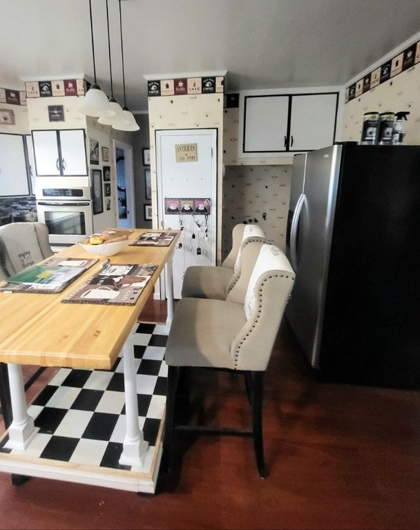 kitchen featuring stainless steel appliances, white cabinetry, and pendant lighting